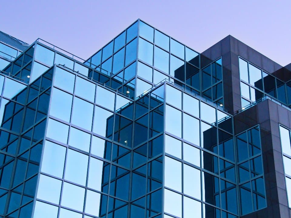 Glass office building facade against a dusk sky